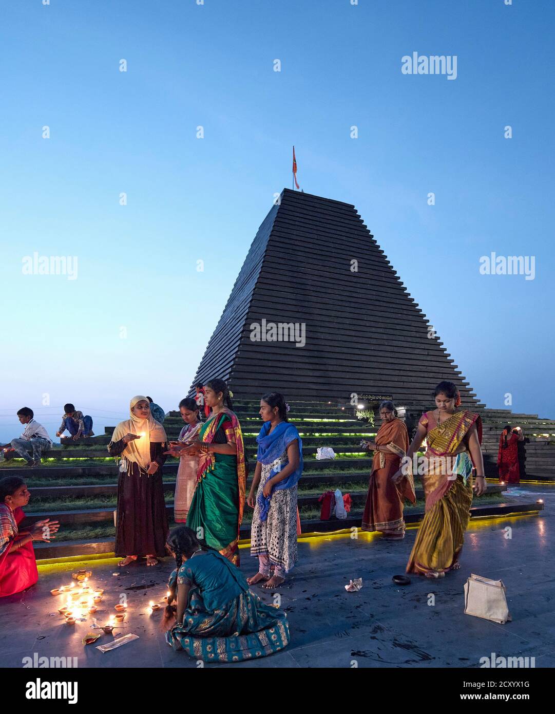 Blick in der Dämmerung mit Dorfbewohnern Beleuchtung Tempel mit Kerzen. Balaji-Tempel, Andhra Pradesh, Indien. Architekt: Sameep Padora und Mitarbeiter , 2020. Stockfoto