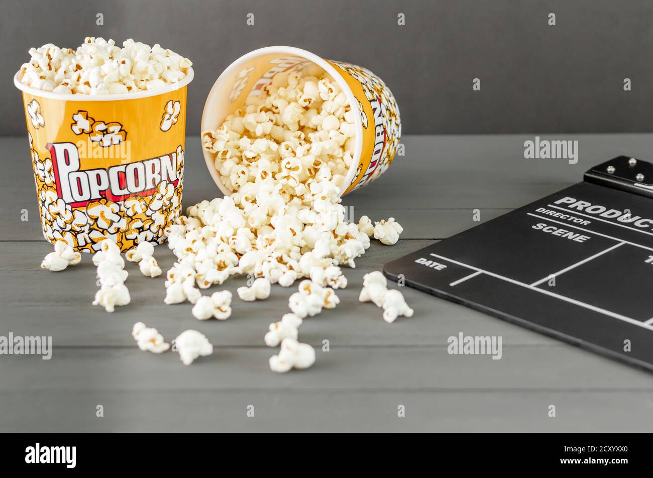 Nahaufnahme, Popcorn Eimer neben einem Klappbrett, auf einem grauen Hintergrund. Konzepte, selektiver Fokus, Film- und Fernsehindustrie Stockfoto