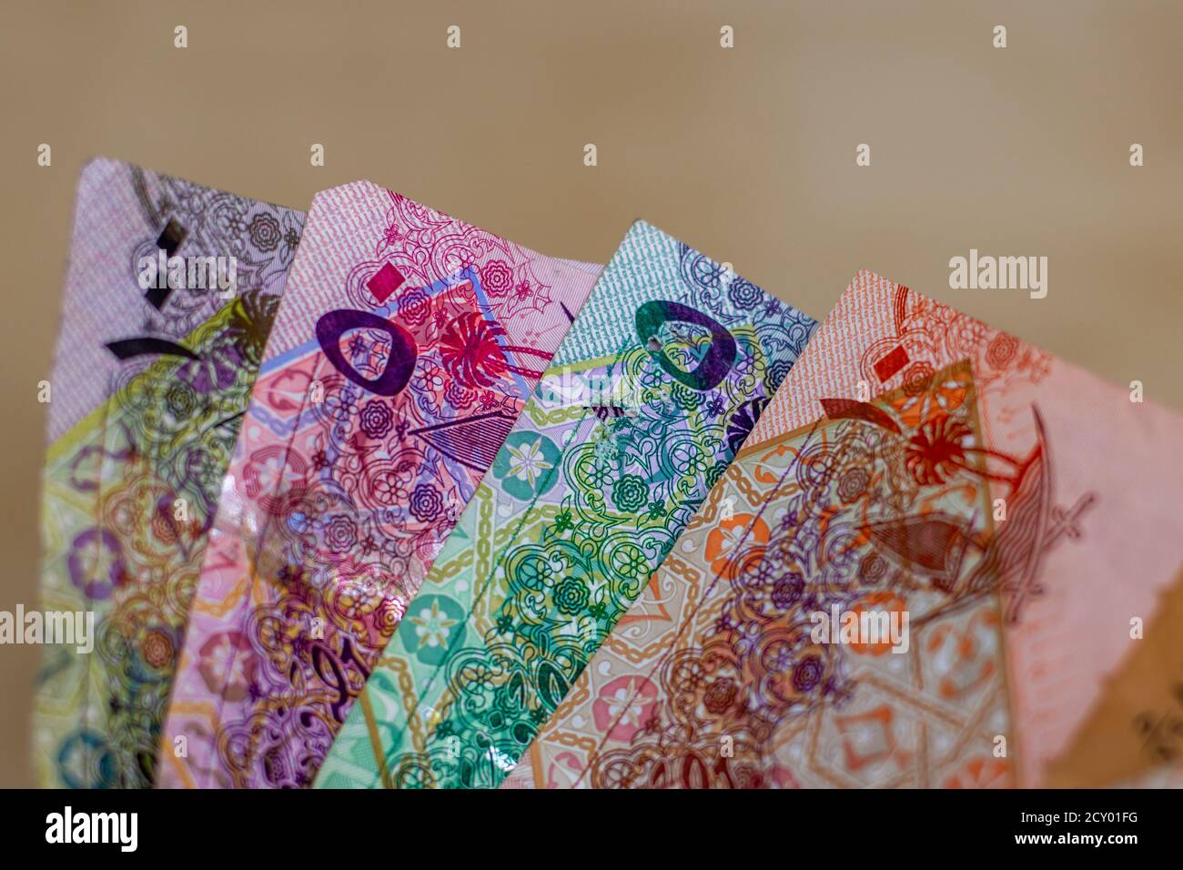 Währung des Katar - Hunderte von rial oder riyal Noten auf einem braunen Hintergrund ausgebreitet. Geldwechsel. Stockfoto