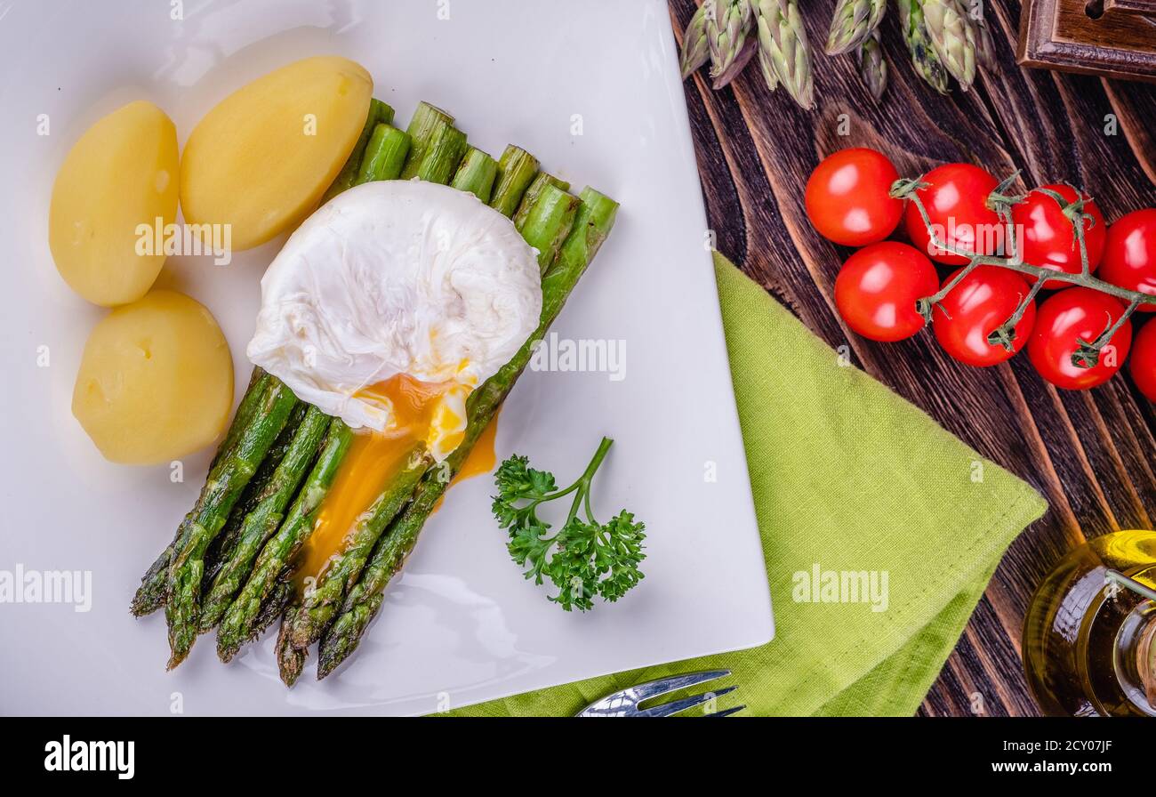 Grüner Spargel und gekochtes pochiertes Ei auf einem weißen Teller. Stockfoto