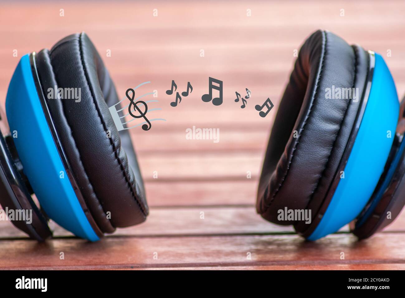Stylischer kabelloser Kopfhörer mit blauer Ohrmuschel für entspanntes Musikhören Musik mit visualisierten Noten, die aus den Ohrmuscheln kommen Um seine Musik zu zeigen Stockfoto