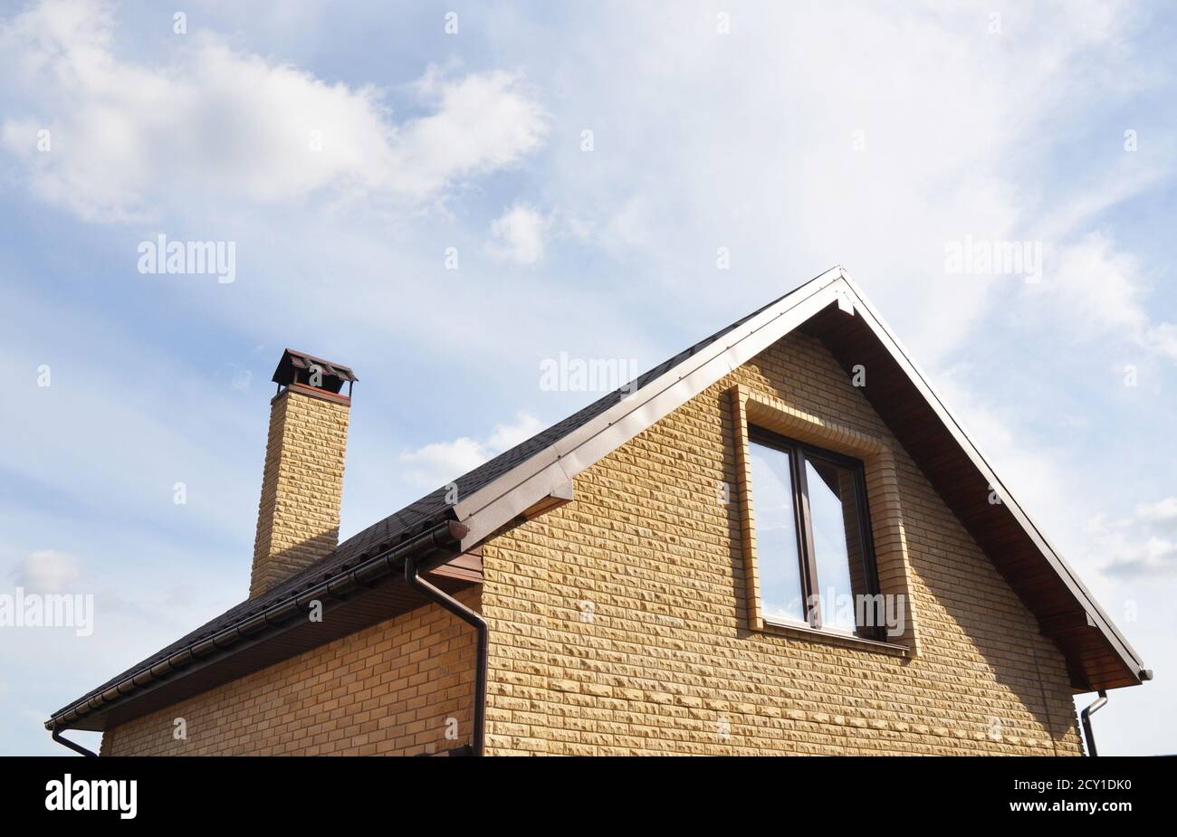 Dachgeschosskonstruktion im Freien. Dachkonstruktion mit Ziegelkamin und Dachrinnen-System. Mansardendach. Stockfoto