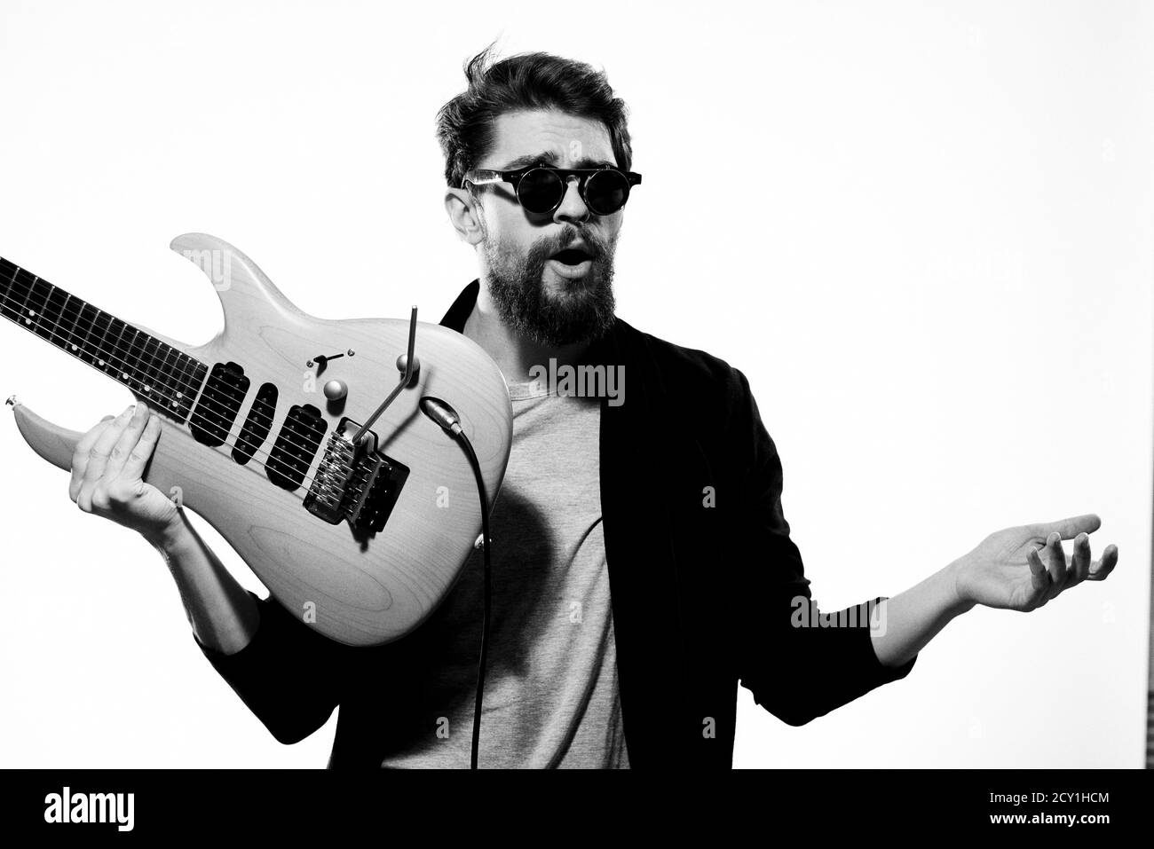 Ein Mann mit einer Gitarre Emotionen Musik Spiel Performance Leder Jacke Sonnenbrille Licht Hintergrund Stockfoto