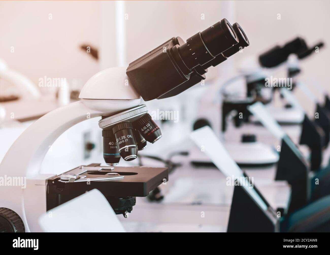 Mikroskop auf dem Tisch im Labor. Linie von Mikroskopen auf Tischen in einem Krankenhauslabor ohne Menschen. Stockfoto
