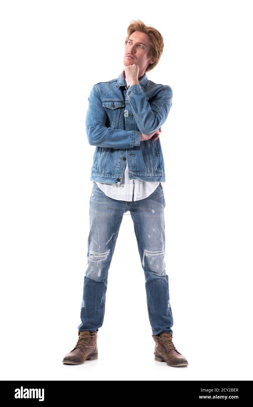 Betrachten junge stilvolle Mann in Jeans Blick nach oben mit Hand auf Kinn. Ganzkörper isoliert auf weißem Hintergrund. Stockfoto