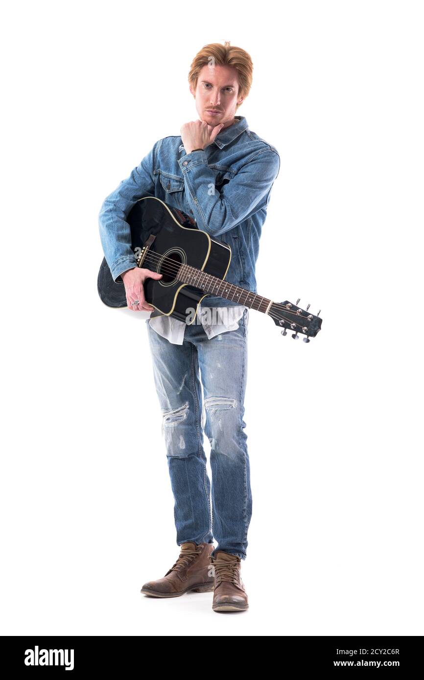 Gutaussehender Rocker oder Country-Gitarrist mit Gitarre posiert mit Hand auf Kinn. Ganzkörper isoliert auf weißem Hintergrund. Stockfoto