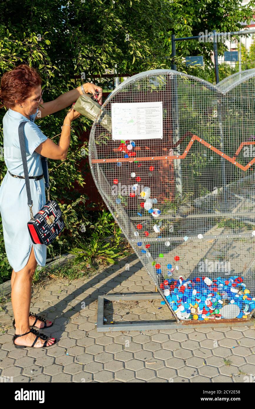 Frau spendet gebrauchte Kunststoffkappen an herzförmigen Recycling-bin Für die Spendenaktion "Caps for the Future" der Wohltätigkeitsinitiative In Sofia Bulgarien Stockfoto