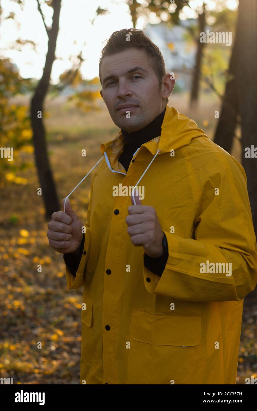 Selbstbewusster Mann im gelben Regenmantel im Herbst Park, Stockfoto