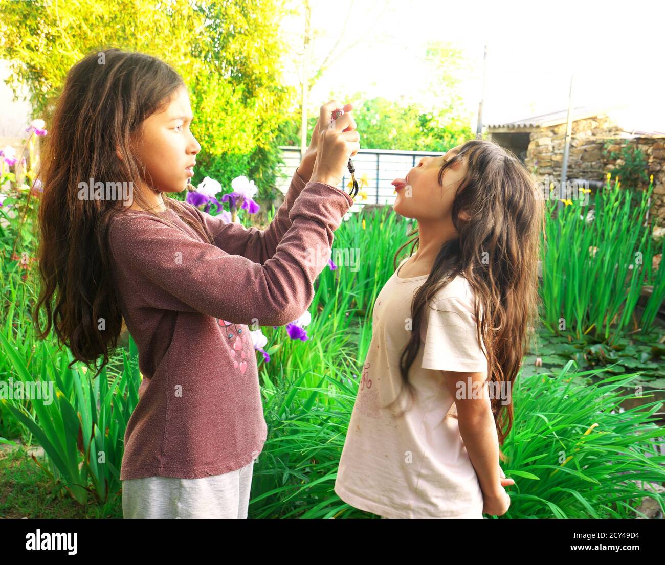 Kleines Mädchen macht einen Grimasse, während ihre ältere Schwester macht ihr Bild. Stockfoto