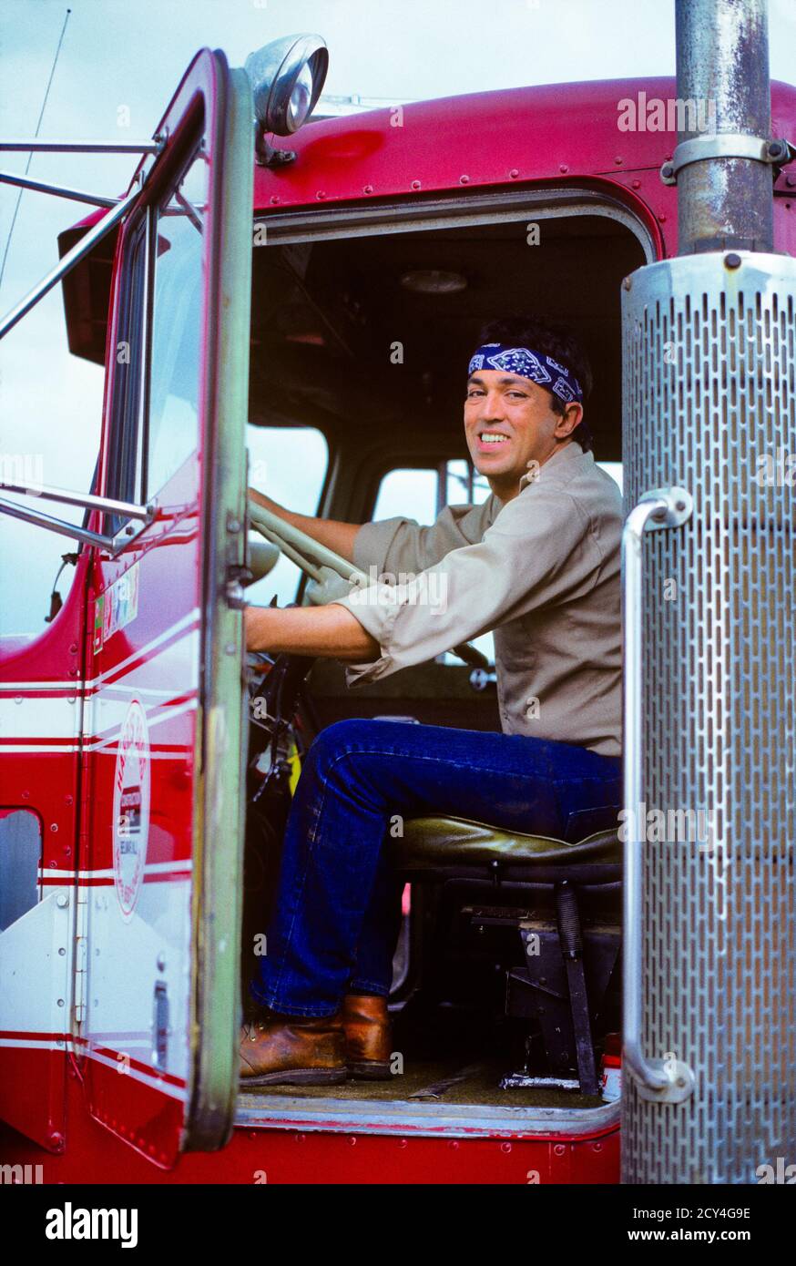 80ER JAHRE HISPANIC MANN ÜBER DER STRASSE LKW-FAHRER SITZT IN SEIN LKW CAB ÖFFNET TÜR LÄCHELND BLICK AUF KAMERA MACHEN EINE LIEFERUNG - KM6656 KRU001 HARS GESICHTSMOTOR KARRIERE FAHRZEUG SICHERHEIT ÖFFENTLICH SPANISCHEN WETTBEWERB ERFREUT FREUDE LIFESTYLE GESCHWINDIGKEIT ZUFRIEDENHEIT CAB JOBS LÄNDLICHE GESUNDHEIT SITZENDEN TRANSPORT KOPIEREN RAUM IN VOLLER LÄNGE PERSONEN PFLEGE MÄNNER RISIKO BERUF VERTRAUEN TRANSPORT FRACHT AUSDRÜCKE BLICKKONTAKT ERFOLG GESCHICKLICHKEIT BERUF GLÜCK FÄHIGKEITEN WELLNESS FRÖHLICH SEINE STÄRKE KUNDENSERVICE KARRIERE AUSSENARBEIT STOLZ A IN DER BESCHÄFTIGUNG MOTORING BERUFE SMILES-VERBINDUNG KONZEPTIONELL Stockfoto