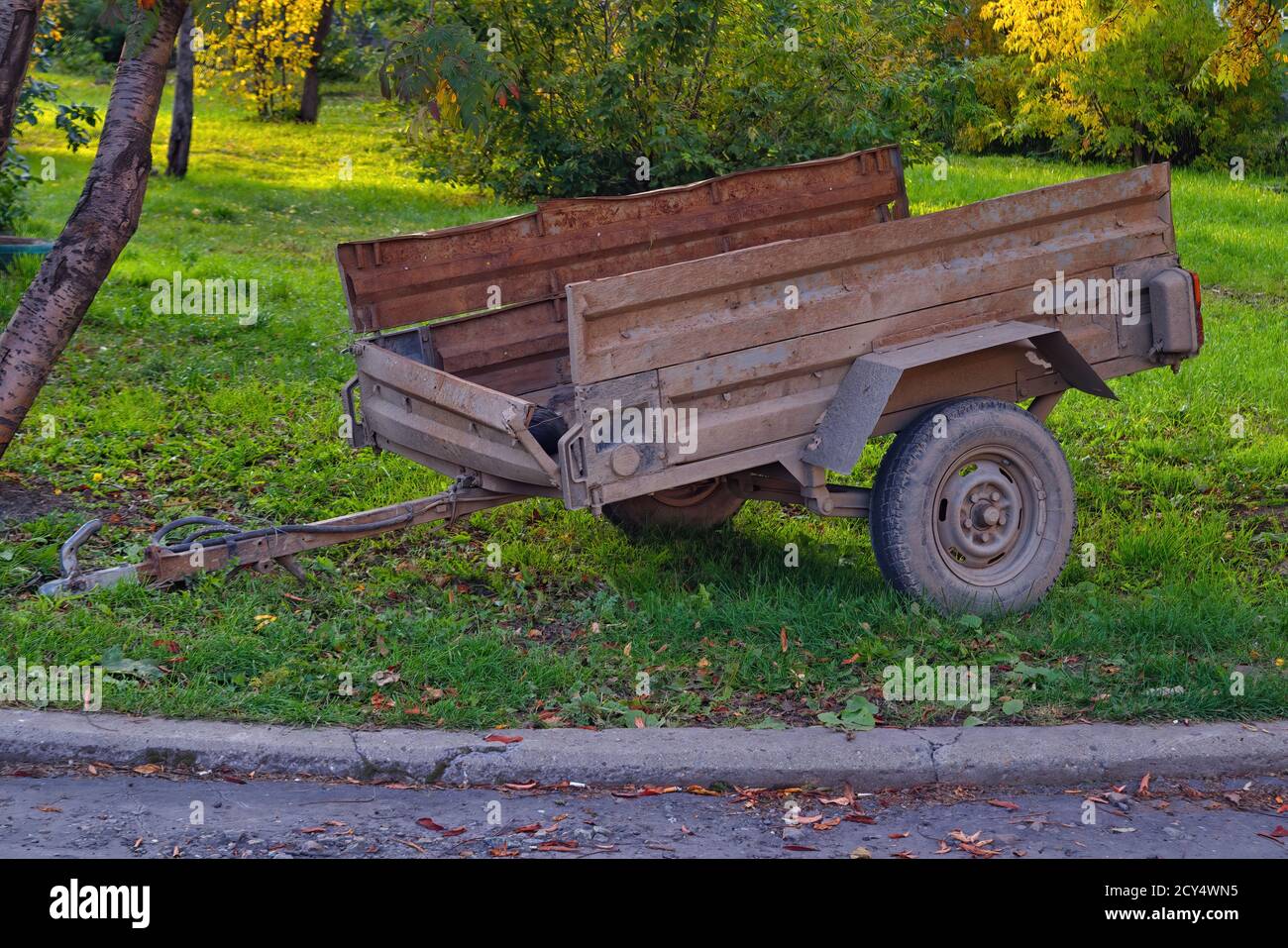 Ein alter Anhänger steht auf dem grünen Rasen. Alter offener Anhänger. Stockfoto