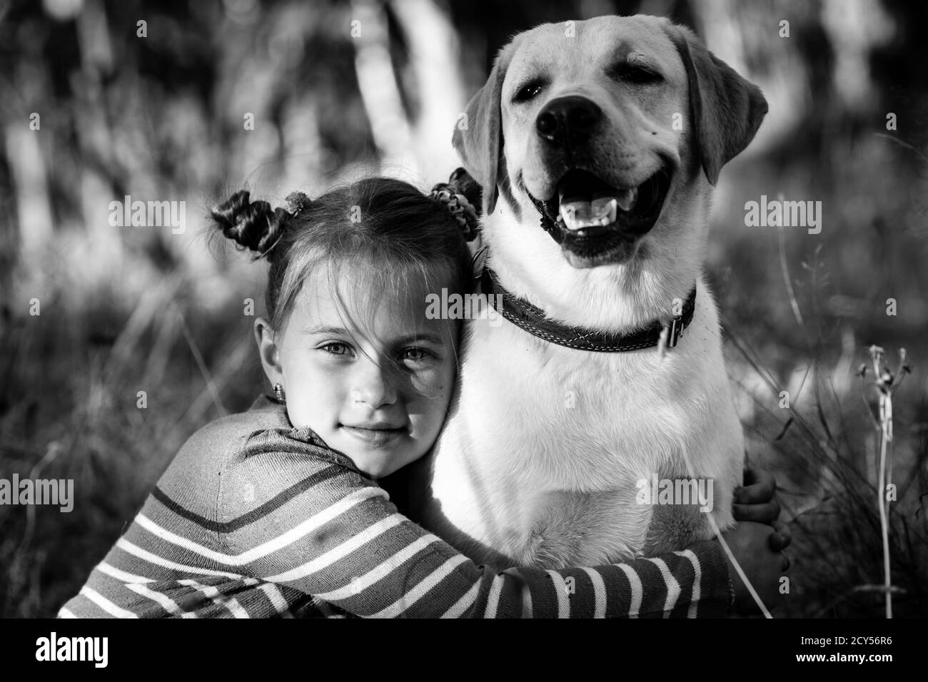 Kleines Mädchen und ihr Hund, draußen. Schwarzweiß-Foto. Stockfoto