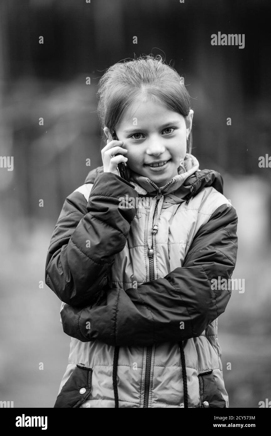 Kleines Mädchen im Gespräch am Telefon, im Freien Porträt. Schwarzweiß-Foto. Stockfoto