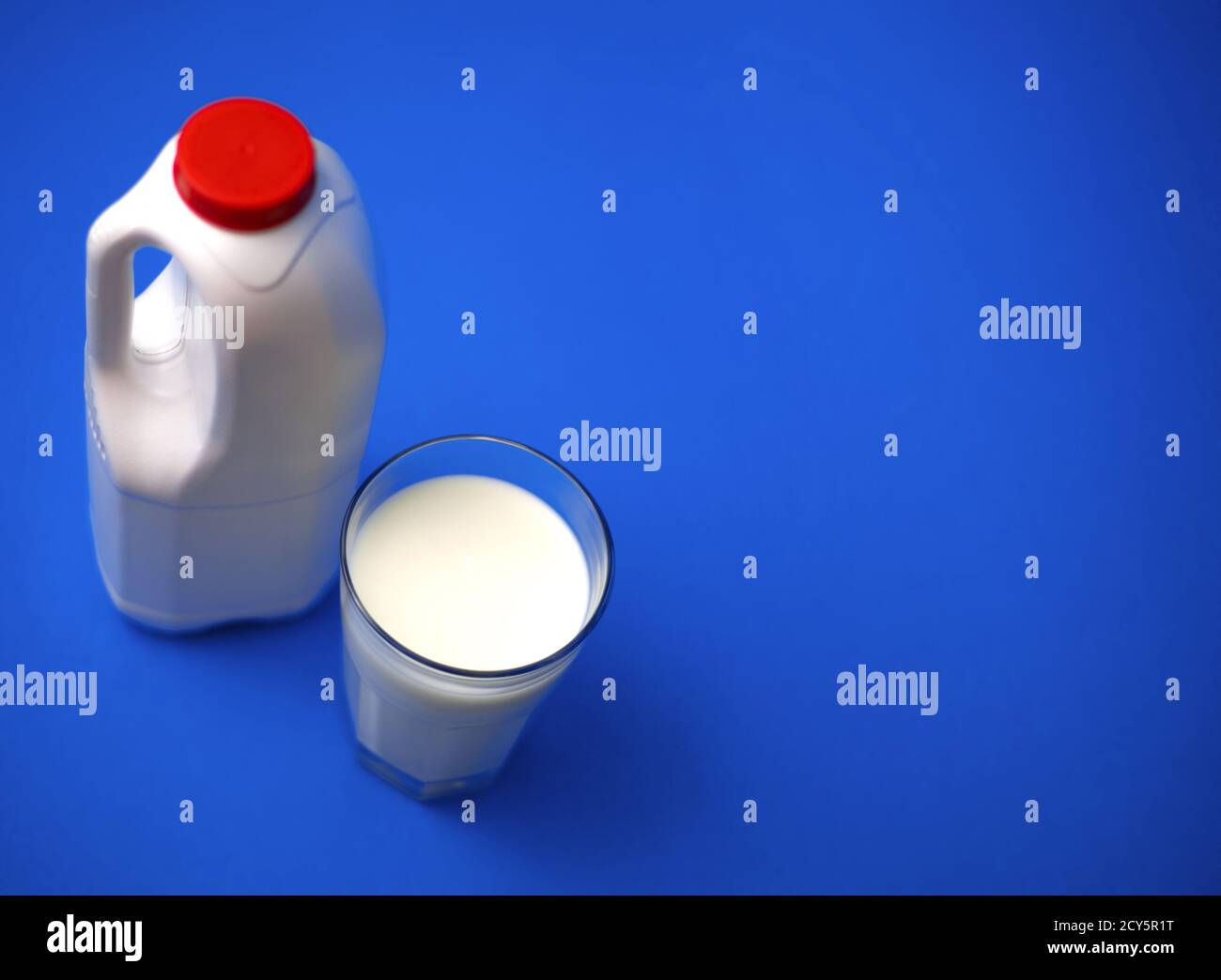 Eine Gallone Milchkännchen mit einem roten Deckel und luftdicht Vollglas Milch auf blauem Hintergrund Stockfoto