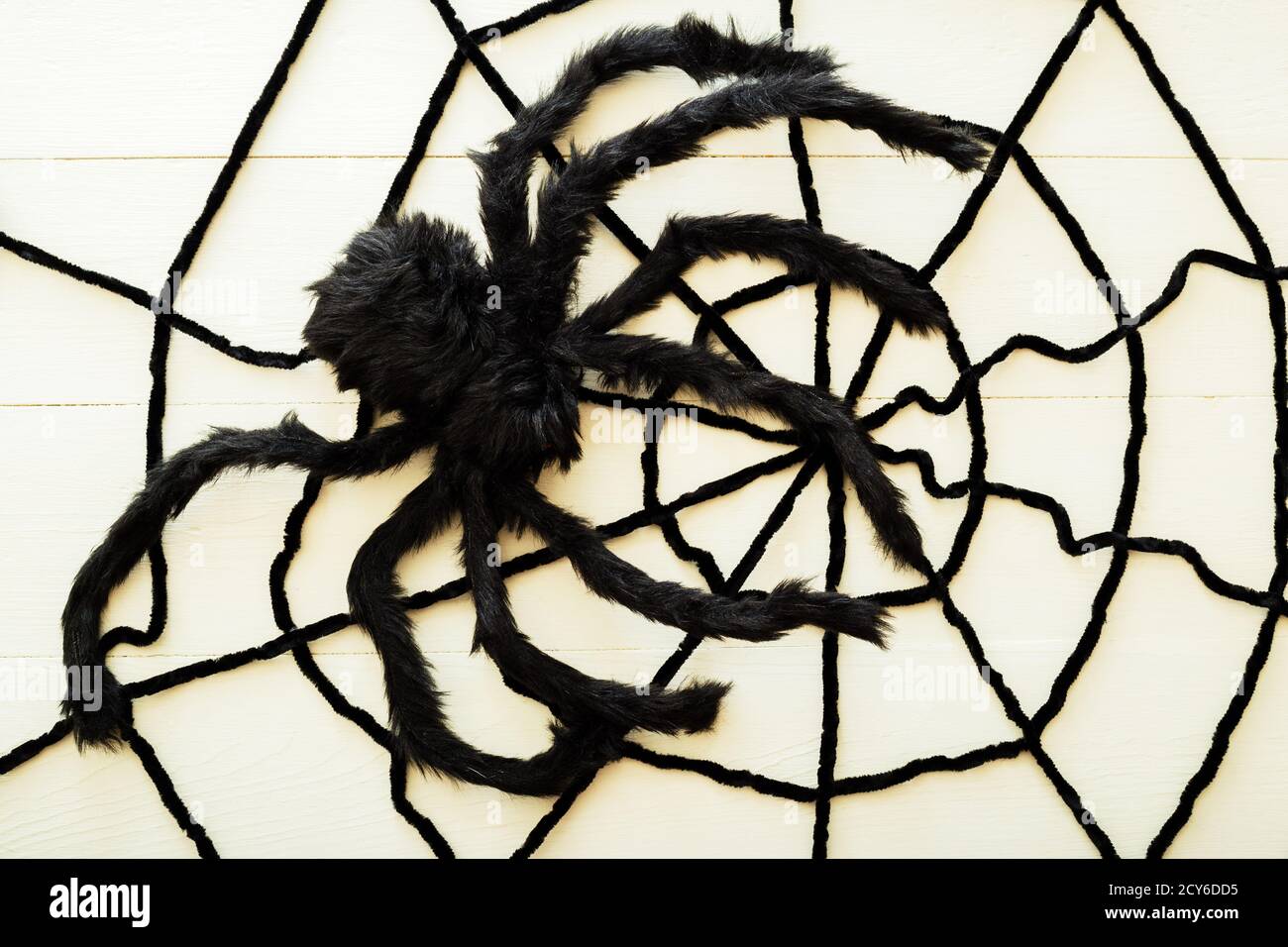 Riesige Spinne auf einem Netz auf einem weißen Holzhintergrund. Halloween Dekorationen Konzept. Flach liegend, Draufsicht, Kopierbereich. Stockfoto