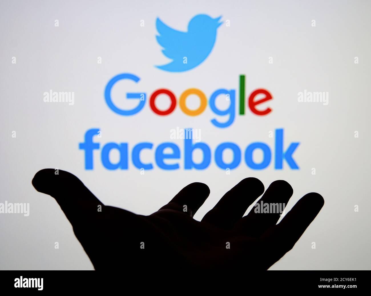 Silhouette der Hand offen und Twitter, Google, Facebook-Logos auf dem unscharfen Bildschirm. Konzept. Stockfoto