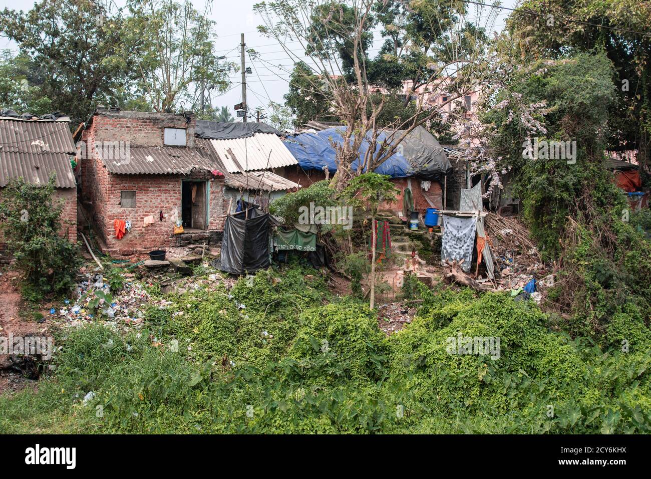 Einfache Wohnhäuser mit Plastikmüll und Wäschetrocknung in den Slums von Bhubaneswar, Indien Stockfoto