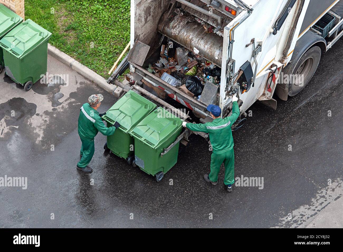 Zwei Arbeiter verladen gemischten Hausmüll in Müllsammelwagen Stockfoto
