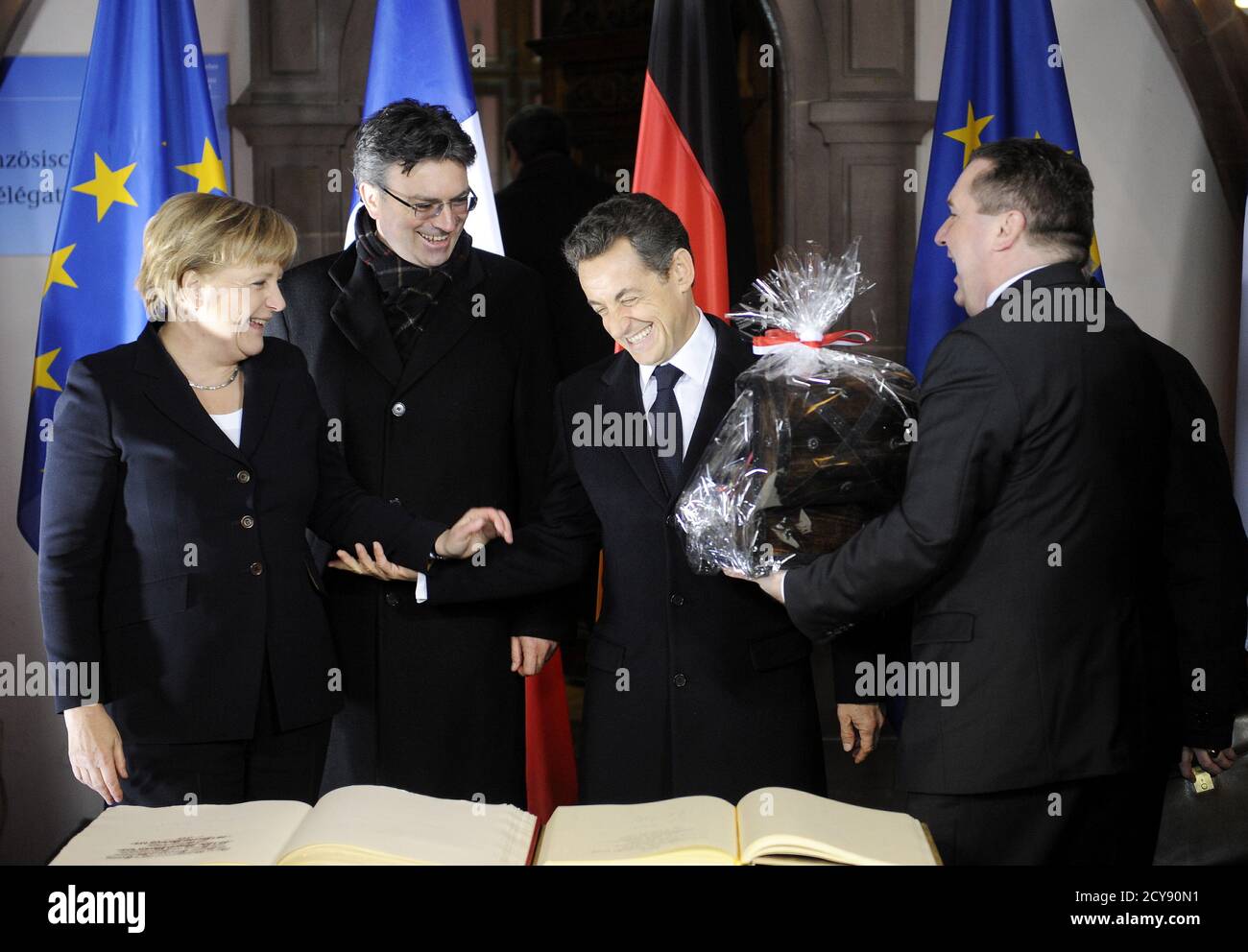 Freiburger Bürgermeister Dieter Salomon (2. L) und Bundeskanzlerin Angela  Merkel sehen zu, wie Baden-Württembergs Ministerpräsident Stefan Mappus (R)  nach der Unterzeichnung des Gästebuch im historischen Rathaus in Freiburg  am 10. Dezember 2010