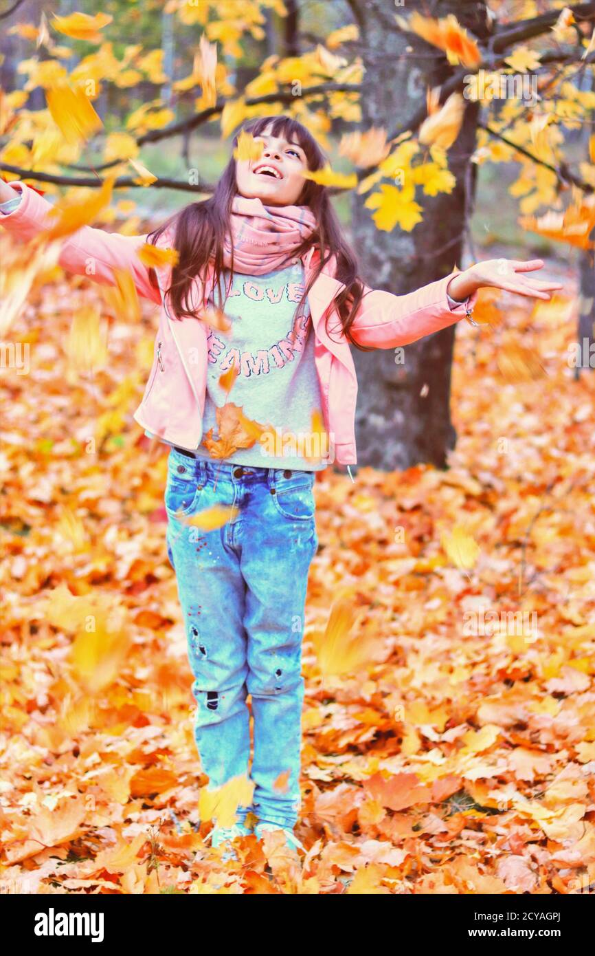 Tolle Herbstsaison. Nettes Teenager-Mädchen spielen mit gelben trockenen Blättern in einem Park und lachen Stockfoto