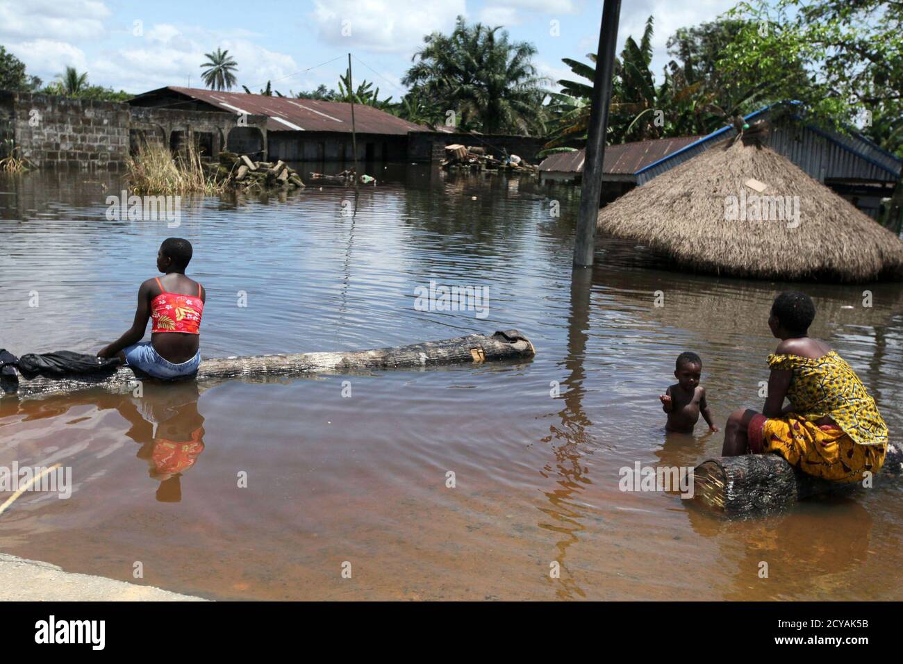 Menschen sitzen vor einem untergetauchten Gebäude in der Patani-Gemeinde im nigerianischen Delta-Staat 15. Oktober 2012. Weite Teile der bevölkerungsreichsten Nation Afrikas wurden in den letzten Wochen von Überschwemmungen überflutet, da große Flüsse wie der Niger, der drittlängste des Kontinents, ihre Ufer sprengen. Mindestens 140 Menschen wurden getötet, Hunderttausende entwurzelt und Zehntausende Hektar Ackerland sind seit Anfang Juli untergetaucht worden, was Bedenken hinsichtlich der Ernährungssicherheit aufwirft, sagte die National Emergency Management Agency (NEMA). REUTERS/Afolabi Sotunde (NIGERIA - Tags: DESASTER SOCI Stockfoto
