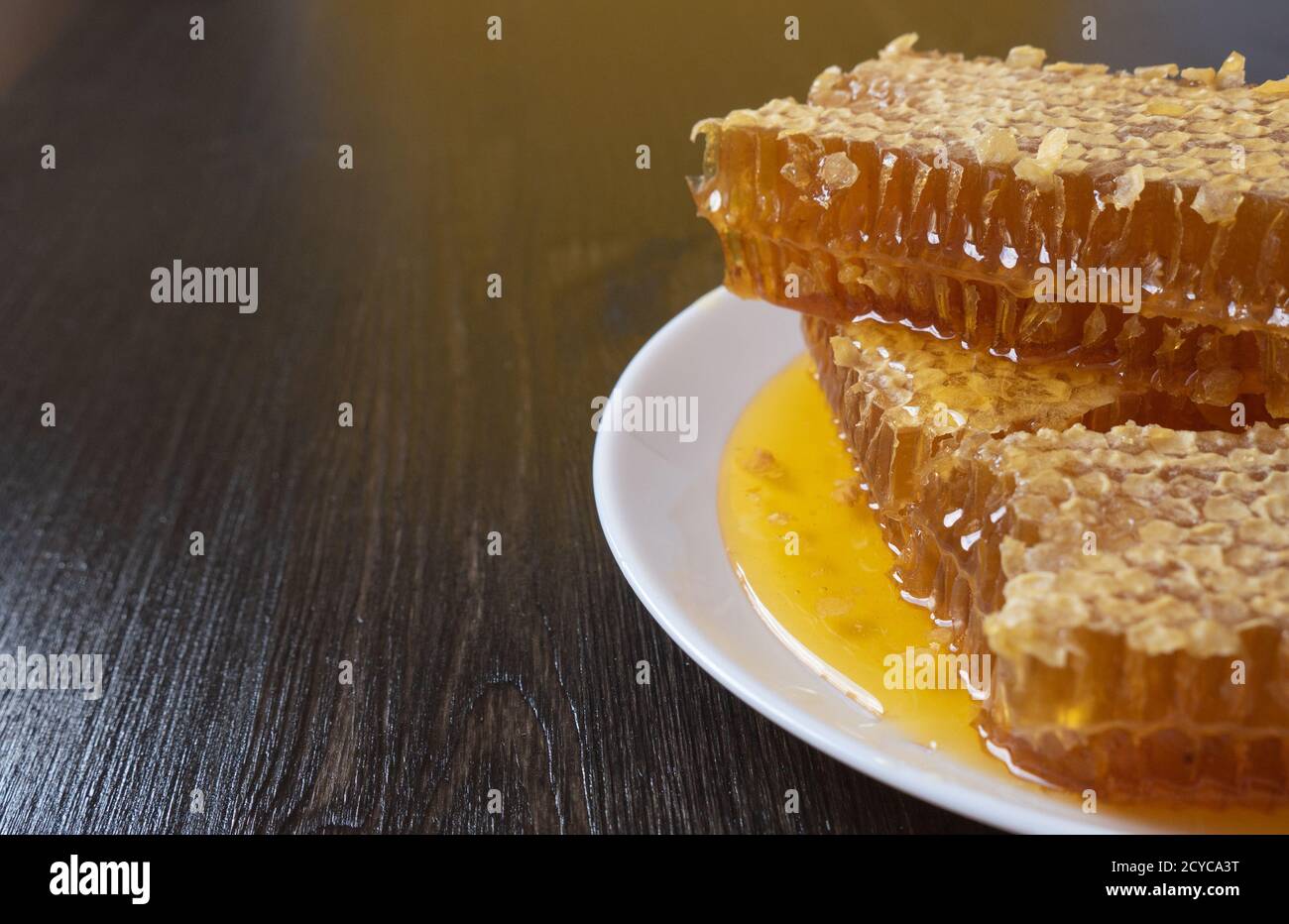 Waben in weißer Platte auf dem Holztisch. Natürliches Bio-Bienenprodukt. Gesunder Lebensstil. Platz für Text kopieren. Nahaufnahme. Stockfoto