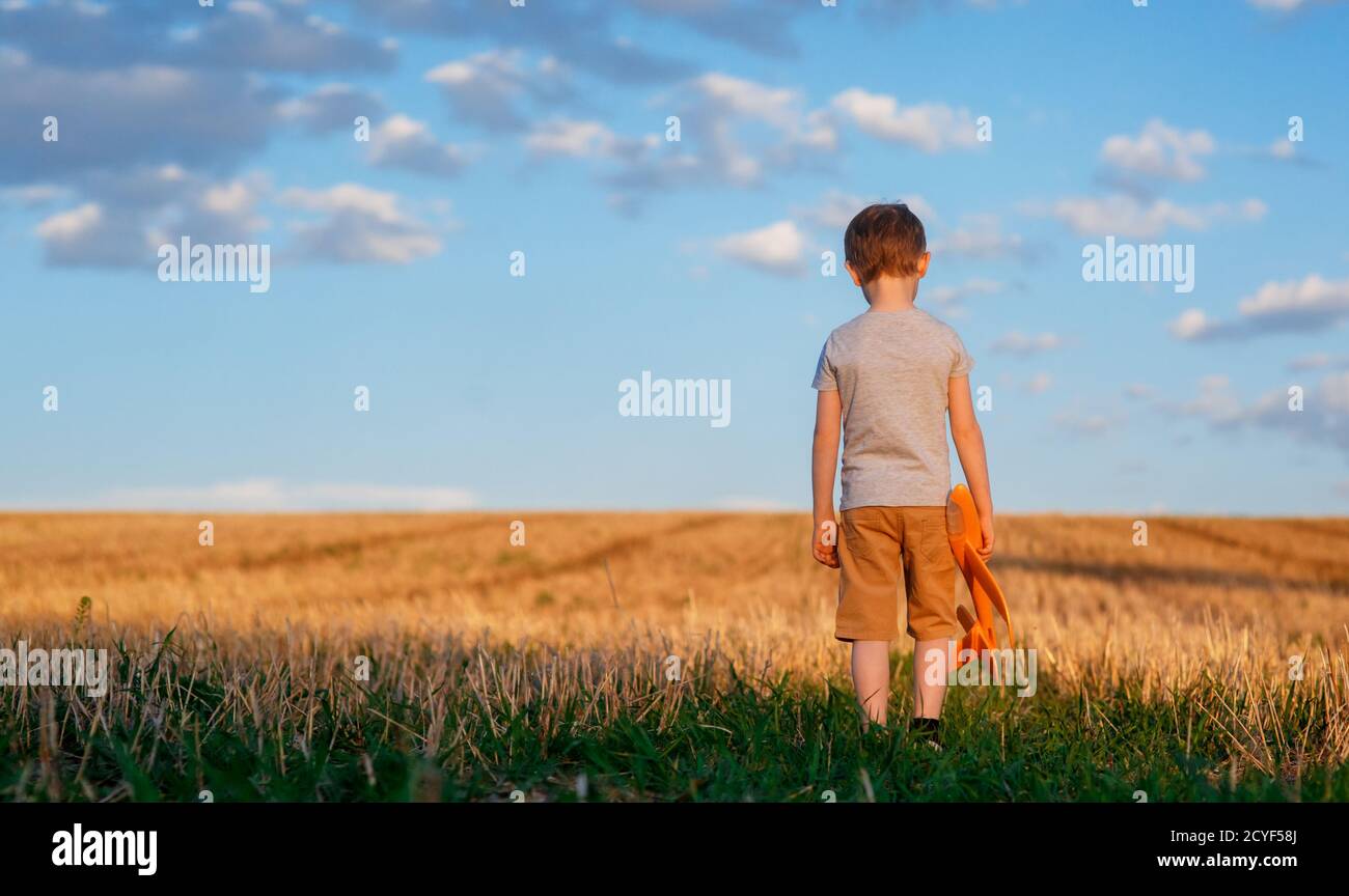 Happy Kind läuft mit Spielzeug Flugzeug auf Himmel Hintergrund glücklich Familie Konzept. Kindheitstraum Stockfoto