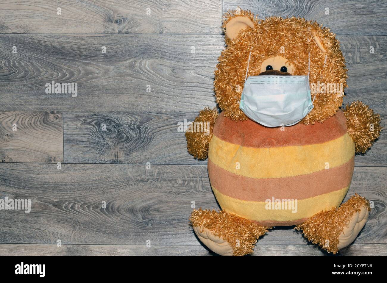 Teddybär mit medizinischer Maske isoliert auf Holz Hintergrund Stockfoto