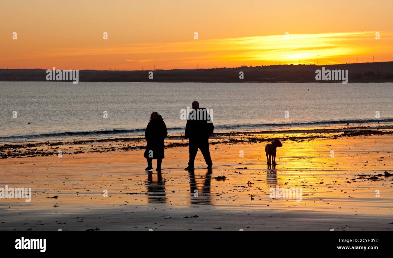 Portobello, Edinburgh, Schottland, Großbritannien. Oktober 2020. Temperatur 3 Grad am Meer als aktive Menschen bei Sonnenaufgang raus. Im Bild: Mann und Frau gehen mit ihrem Hund. Stockfoto