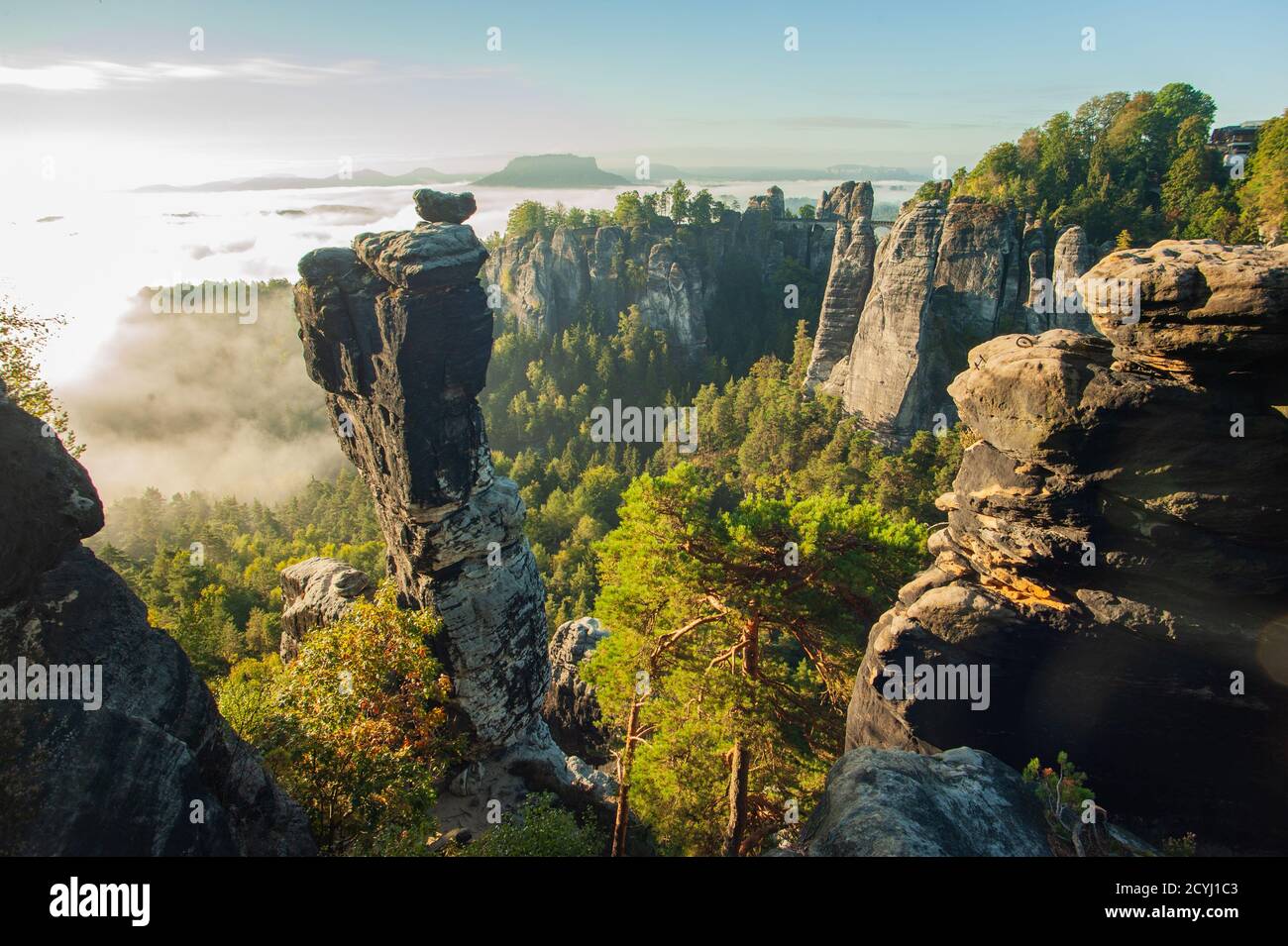 Malerischer Blick über den Wehl-Boden auf die Bastei-Brücke mit Nebel im Tal beim Sonnenaufgang. Die markante Wehl-Nadel im Vordergrund. Stockfoto