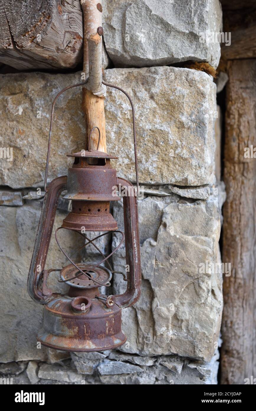 Alte Rusty Öl Lampe hängend auf rustikalen Holz Haken in Steinmauer Stockfoto