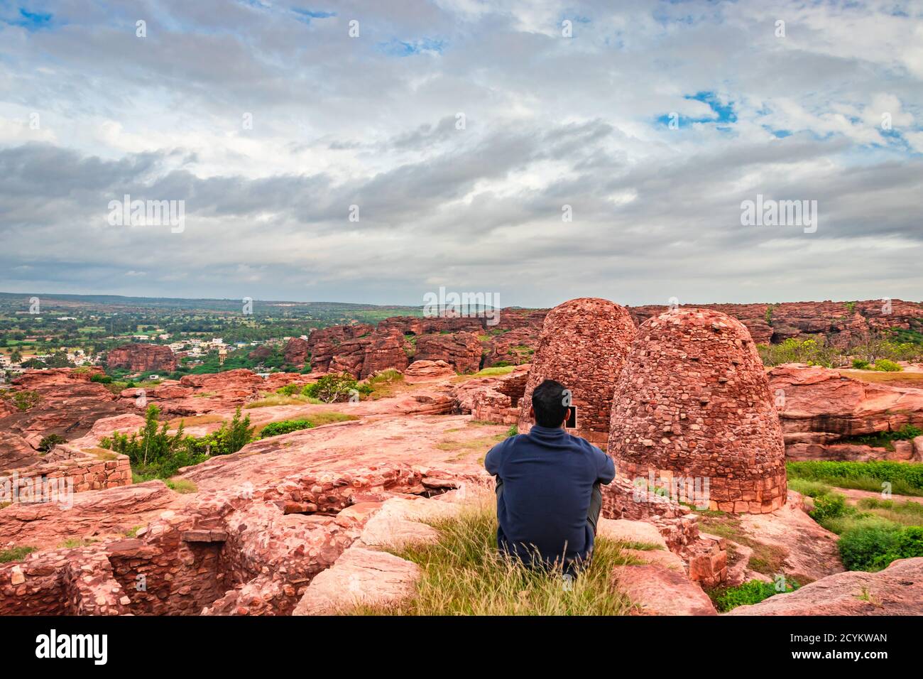 Mann sitzt auf der Bergspitze und beobachten die Ruinen der historischen Festung am Morgen Bild wird bei badami karnataka indien genommen. Stockfoto