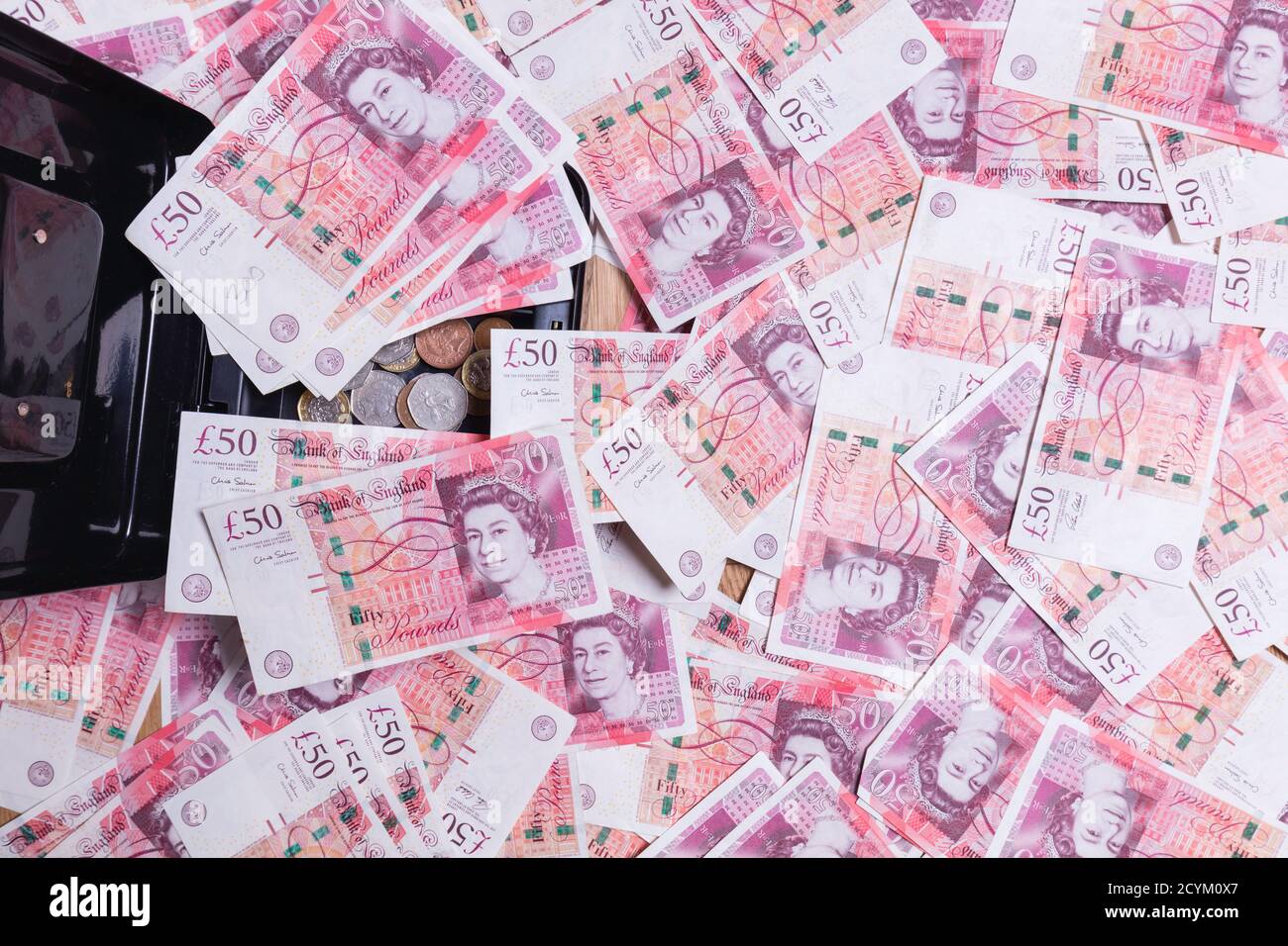 £50 Banknoten, die aus einer schwarzen Kasse überlaufen. Stockfoto