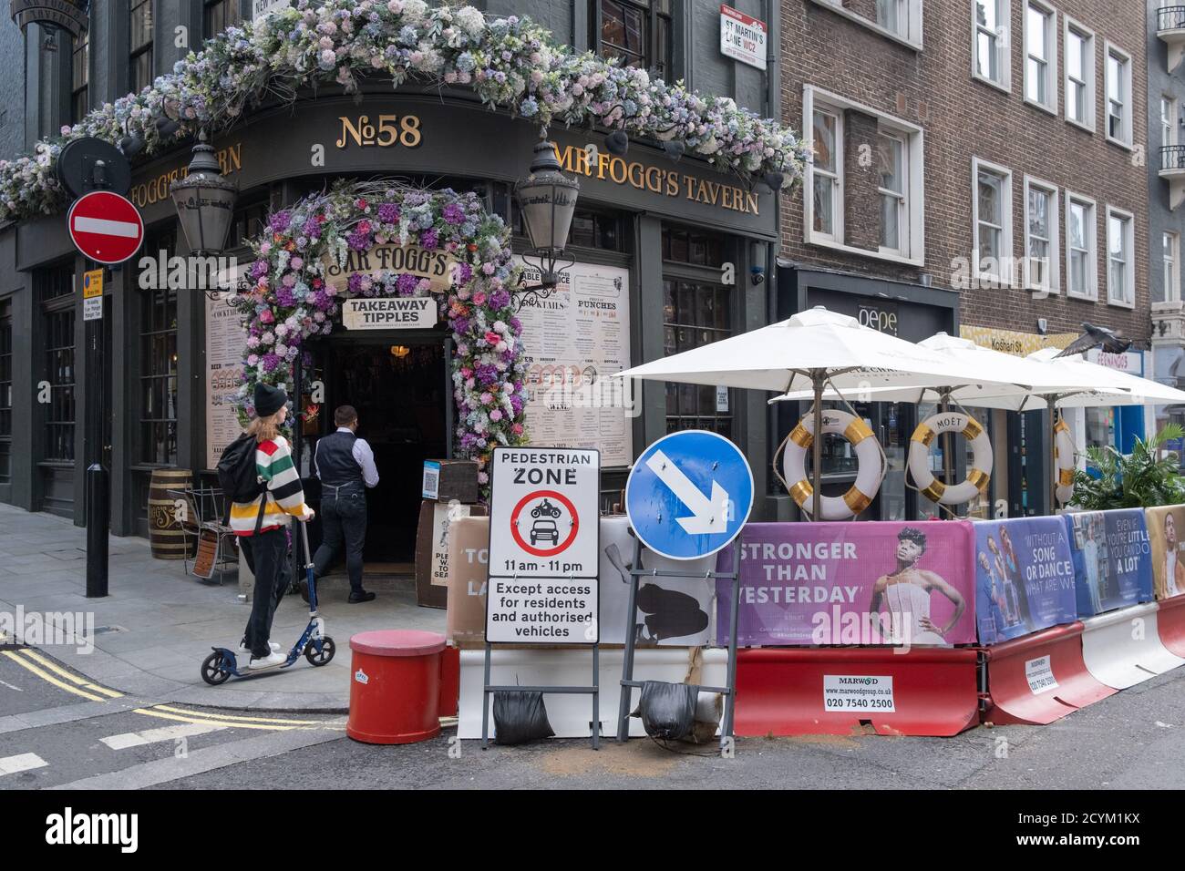 Fußgänger gehen die St. Martin's Lane entlang im Herzen des West End Theatreland der Hauptstadt, wo Straßensperren mit einigen der vielen Musik- und Bühnenstücke auf sozialen Fernstraßen-Barrieren während der Coronavirus-Pandemie am 29. September 2020 in London, Westminster, England, zu sehen sind. Trotz des £1,15 Mrd. finanziellen Rettungspakets der Regierung für die Kunstindustrie und kulturelle Organisationen in England, bestehend aus £880 Mio. an Zuschüssen und £270 Mio. an rückzahlbaren Darlehen, Londons Theaterindustrie wurde hart von der Pandemie getroffen, die seit der März Schließung geschlossen hat, die eine hat Stockfoto