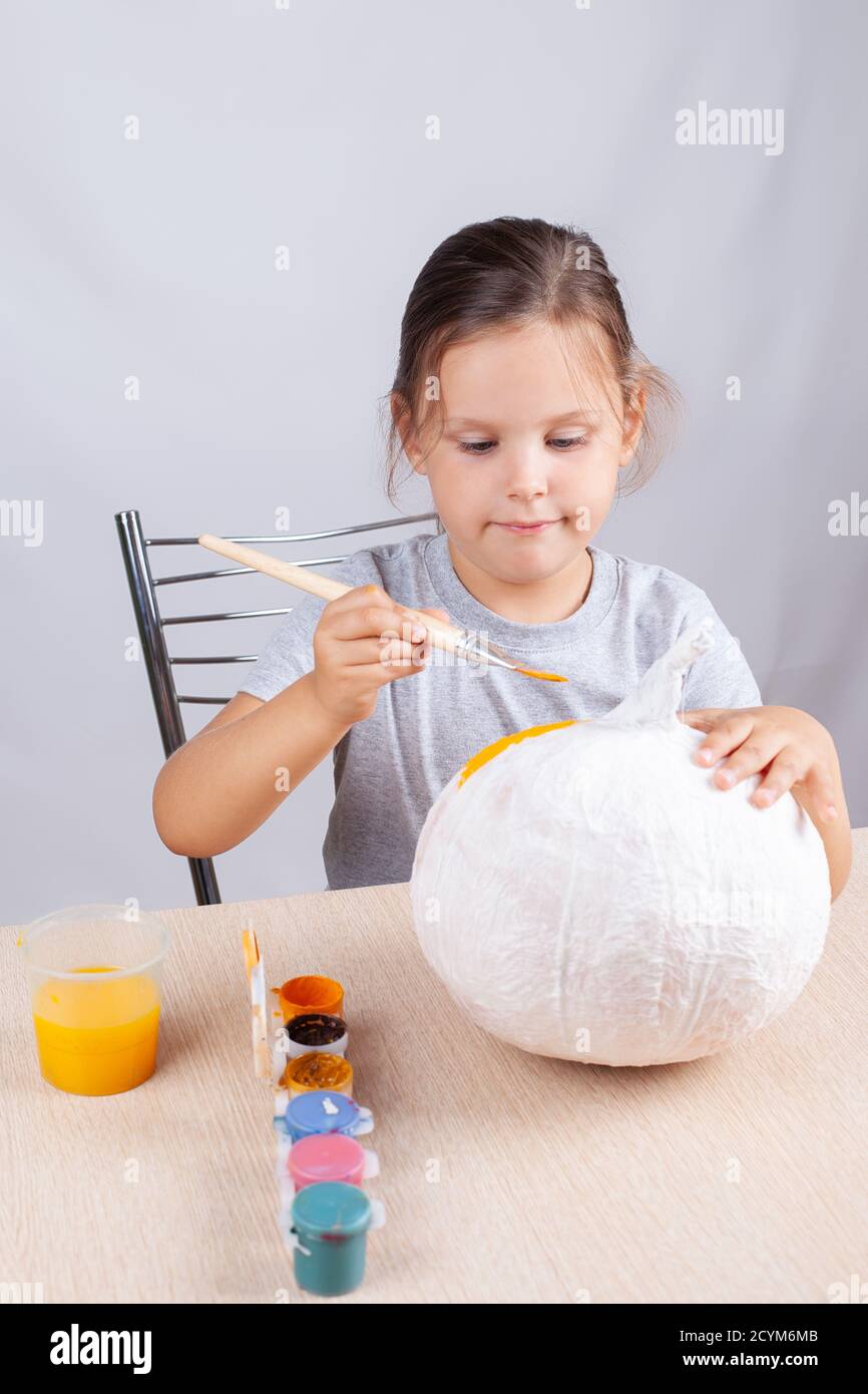 Selbstgemachte Deko für Halloween malt ein Kind einen Kürbis aus Papier und Servietten, ein Hobby auf Selbstisolation Stockfoto