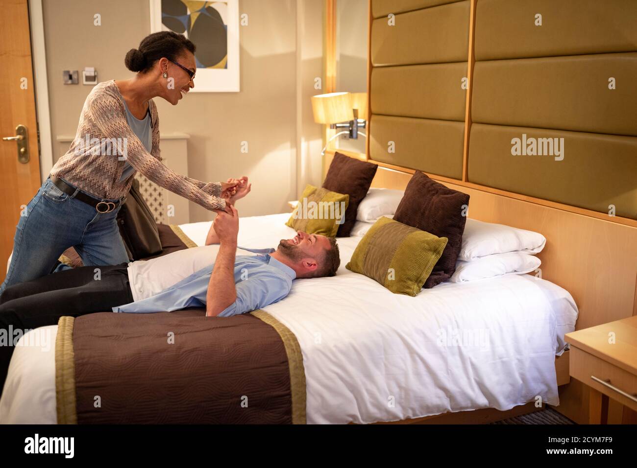 Ein multiethnisches Paar, das in einem Hotelzimmer verspielt ist, hat einen romantischen Abend geplant. Stockfoto