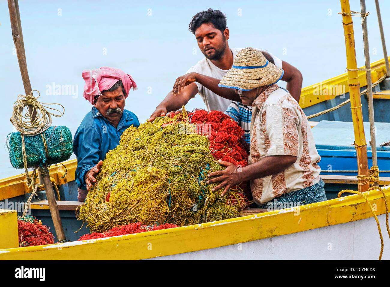 Fischer sammeln Netze auf ihrem Fischerboot, um an den belebten, beliebten Marari Beach zu bringen; Mararikulam, Alappuzha (Alleppey), Kerala, Indien Stockfoto