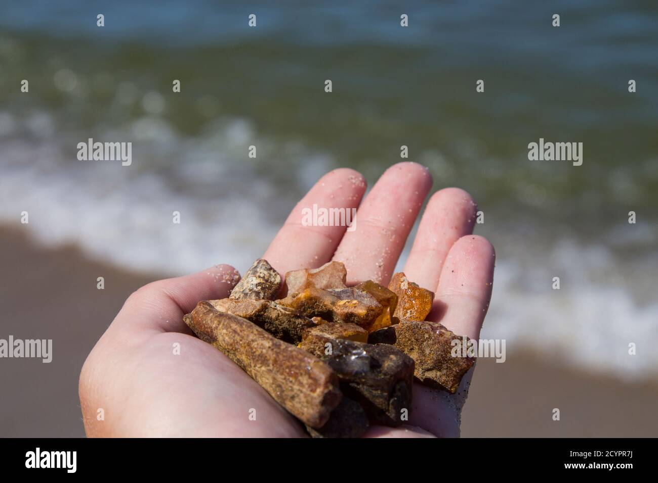 Bernstein nicht in Sand vor dem Hintergrund der Meereswellen verarbeitet. Stockfoto