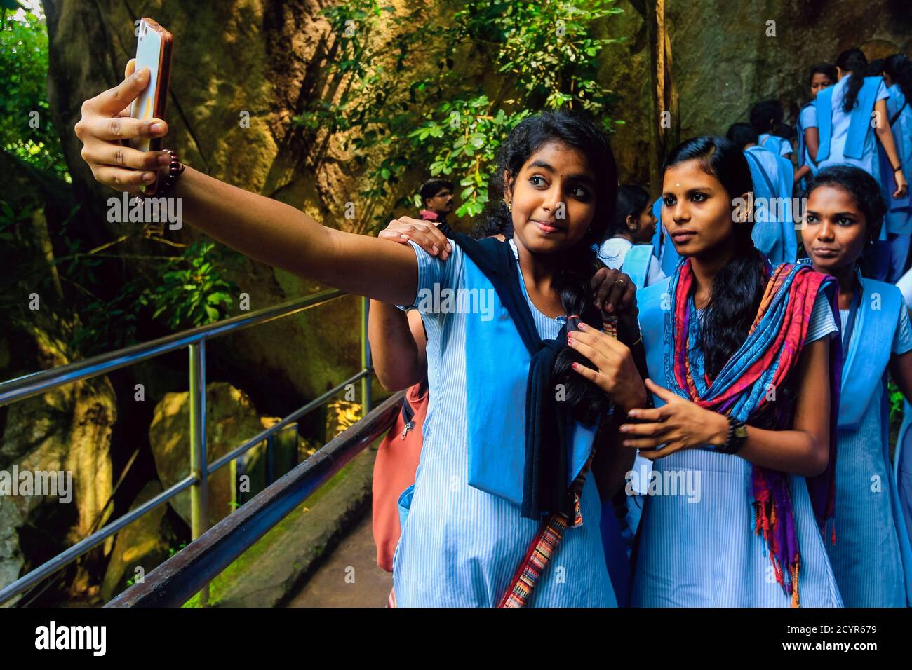 Mädchen im Teenageralter, die ein Handy-Selfie-Foto auf einem Schulausflug zu den historischen Edakkal-Höhlen machen; Edakkal, Ambukutty Mala, Wayanad, Kerala, Indien Stockfoto