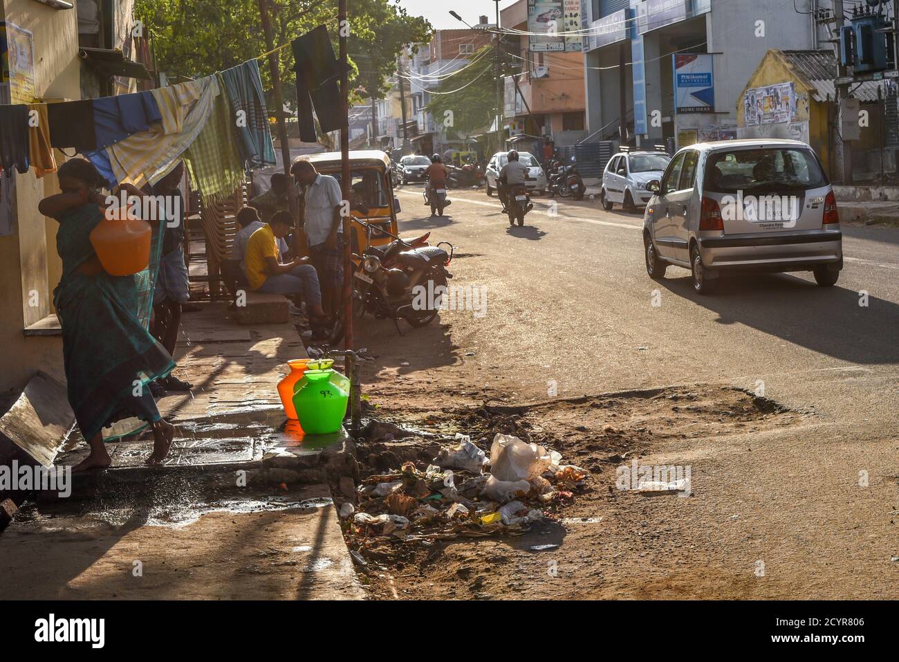 TAMILNADU, INDIEN - 09. FEBRUAR 2016: Eine indische Frau sammelt und trägt Wasser in Plastiktöpfen in einem Slum am Stadtrand von Coimbatore. Stockfoto