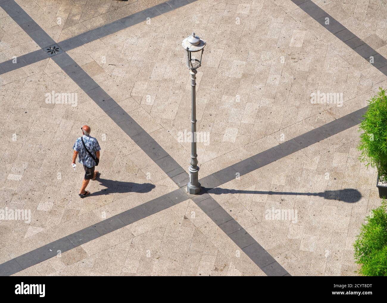 Ein Gentleman mit Handtasche spaziert an einem sonnigen Sommertag auf dem Hauptplatz der Stadt Stockfoto