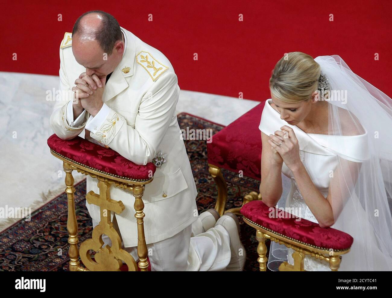 Monacos Fürst Albert II. (L) und Prinzessin Charlene knien am Altar während ihrer religiösen Hochzeitszeremonie im Palast von Monaco am 2. Juli 2011. REUTERS/Lionel Cironneau/Pool (MONACO - Tags: ROYALS UNTERHALTUNG BILD DES TAGES TOP PICTURE) Stockfoto