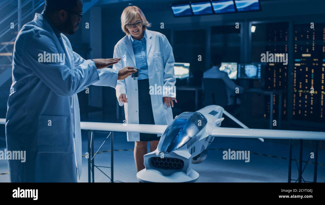 Internationales Team von Luft- und Raumfahrtingenieuren arbeitet an unbemannten Luftfahrzeug Drohne Prototyp. Luftfahrtwissenschaftler sprechen, mit Blueprints. Labor Stockfoto