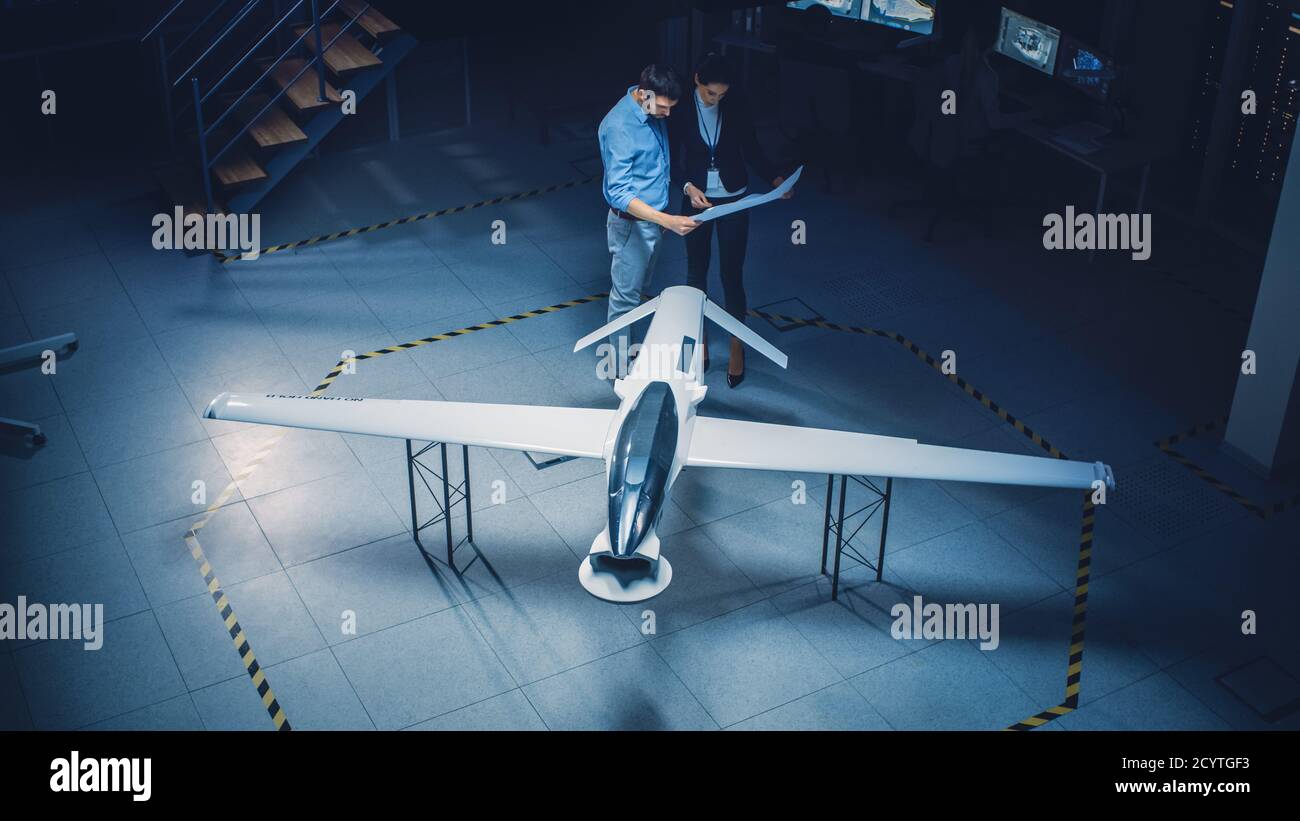 Treffen der Luft- und Raumfahrtingenieure arbeiten an unbemannten Luftfahrzeug Drohne Prototyp. Luftfahrtexperten diskutieren. Industrieanlage mit Flugzeugen Stockfoto