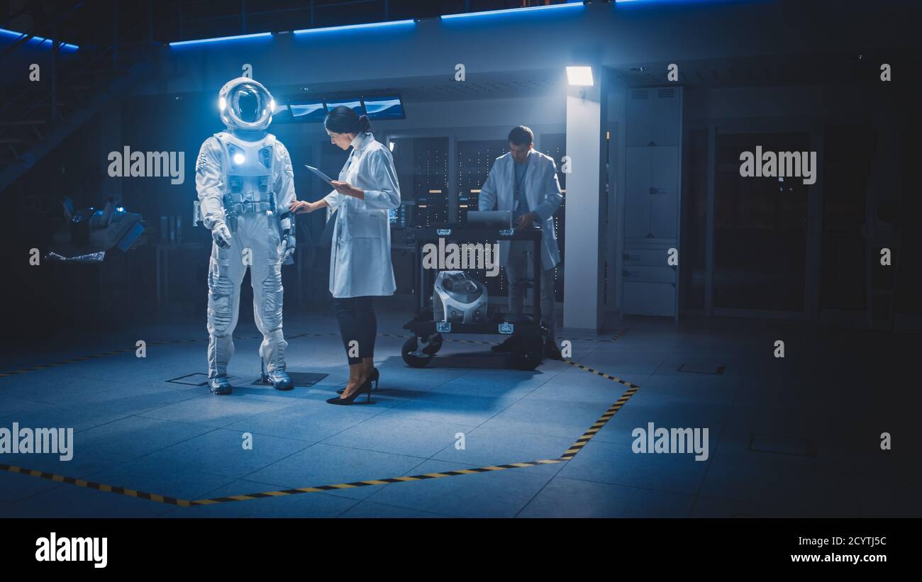 Vielfältiges Team von Luft- und Raumfahrtwissenschaftlern und Ingenieuren in weißen Mäntel Verwenden Sie Computer, um neue Space Suit für Galaxy angepasst zu entwerfen Exploration und Stockfoto