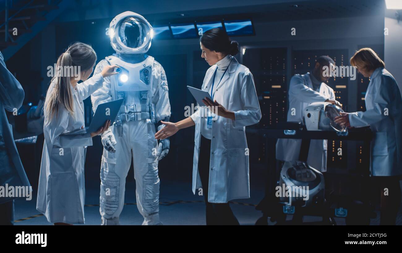 Diverse Team von Luft-und Raumfahrt Wissenschaftler und Ingenieure tragen weiße Mäntel haben Diskussion, verwenden Computer Design neuen Raum Anzug für Galaxy angepasst Stockfoto