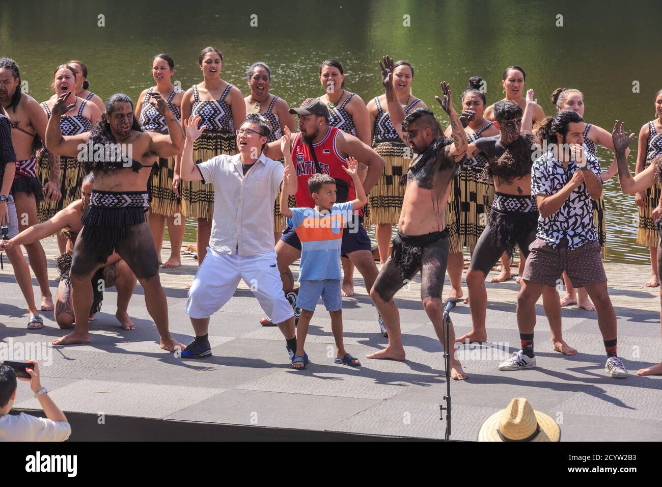 Eine neuseeländische Maori-Kulturgruppe, die auf der Bühne einen Haka (traditionellen Tanz) aufführt, an dem mehrere Touristen teilnehmen. Hamilton, Neuseeland, 23/2019 Stockfoto