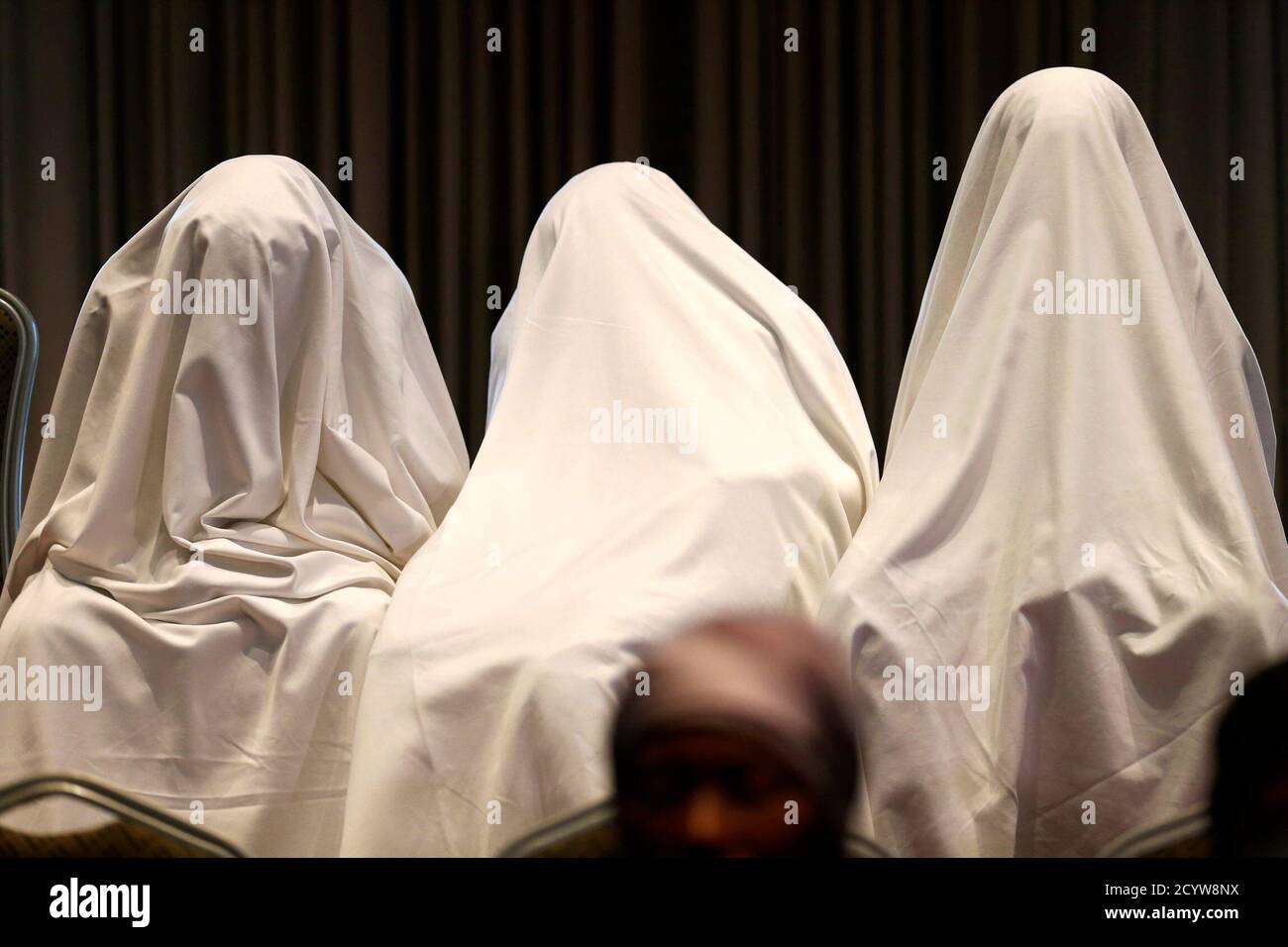 Drei Mädchen, die nach ihrer Entführung im abgelegenen Dorf Chibok entkommen waren, sind am 5. Juni 2014 bei einer Pressekonferenz in Lagos mit weißen Laken bedeckt. Mehrere Mütter von Mädchen, die in Nigeria von der militanten Gruppe Boko Haram festgehalten werden, versammelten sich am Donnerstag in Lagos, wo ihnen Nichtregierungsorganisationen und ein Kongressabgeordneter des US-Bundesstaates Therapie und Unterstützung boten. Boko Haram, eine militante Gruppe, die eine Kampagne zur Schaffung eines islamischen Staates in der Region führte, entführte am 14. April 276 Mädchen einer Schule in Chibok. Die drei Mädchen waren mit weißen Laken bedeckt, um ihre Identität aus Angst zu schützen o Stockfoto