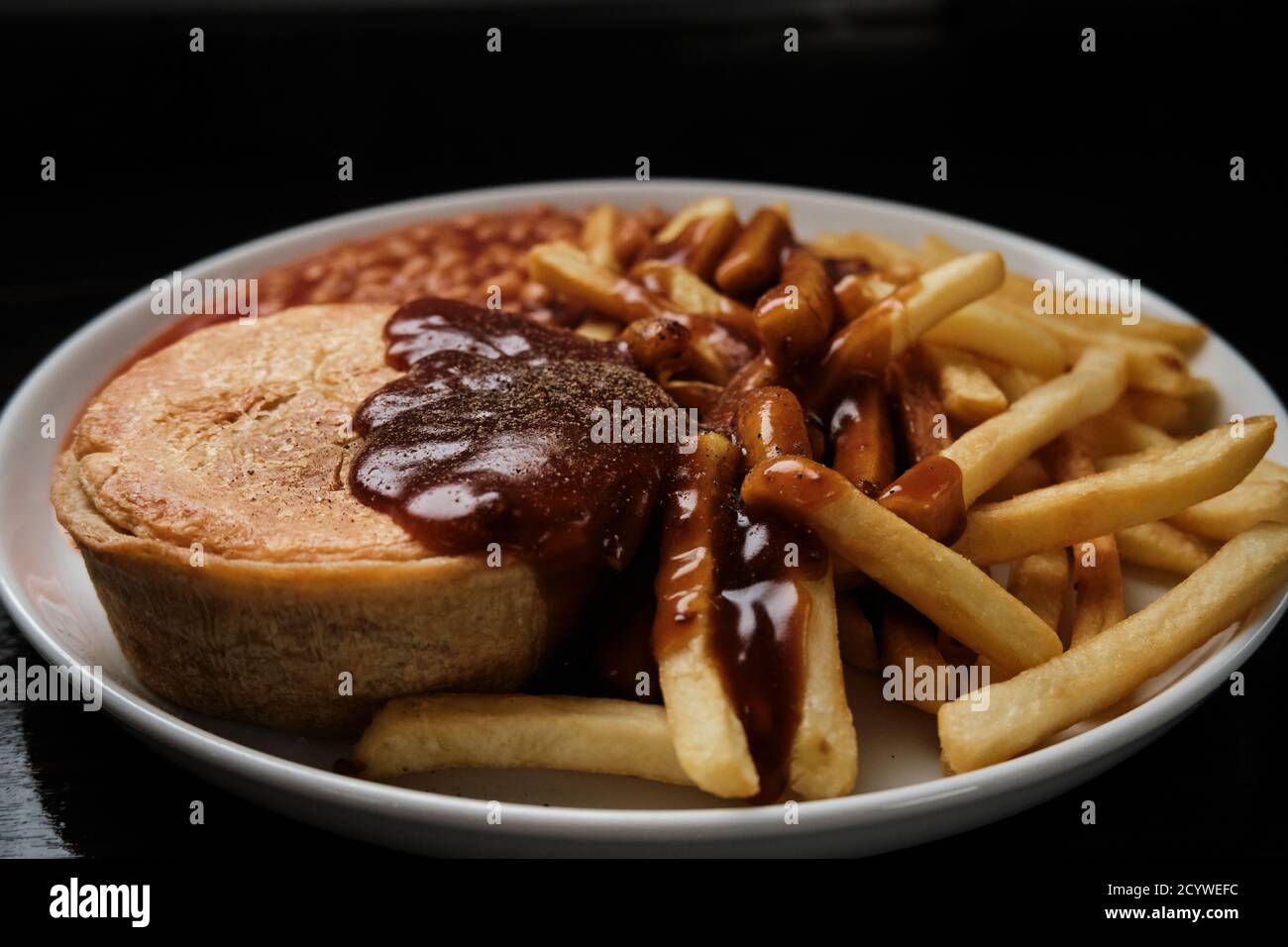 Steak und Kidney Pie, Chips, Bohnen und Soße Stockfoto