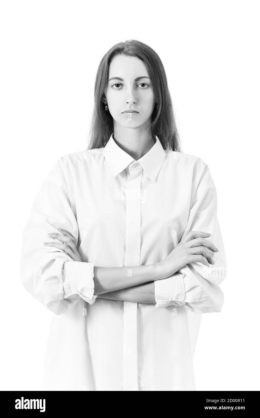 Ernst junge Frau mit gekreuzten Armen in weißer Bluse Blick auf Kamera auf weißem Hintergrund, monochrom Stockfoto